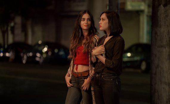 Emma (played by Mishel Prada) and Lyn (played by Melissa Barrera) stand on the sidewalk at night in Vida Season 2