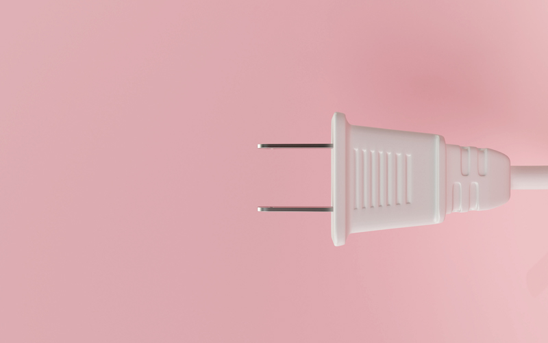 white electrical plug against pink background