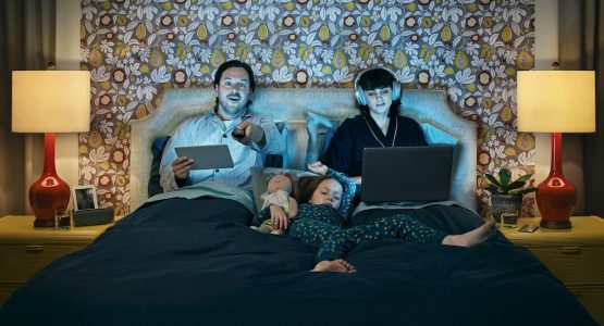 family in bed watching and streaming holiday movies