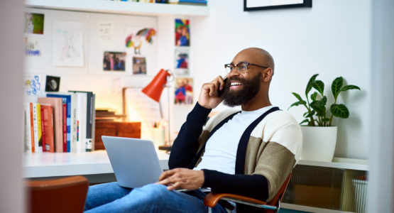 Man in his 30s sitting on chair with laptop, on phone call, communication, owner, entrepreneur